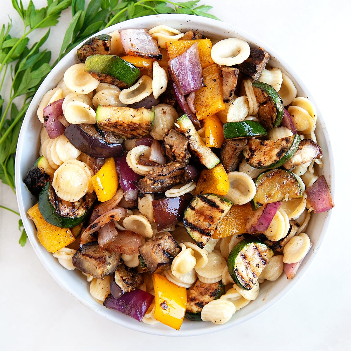 Grilled Vegetable salad with orecchiette pasta in a large white serving bowl, square picture.